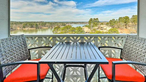 Ein Balkon mit Tisch und Stühlen mit Blick auf einen See und Gebäude.
