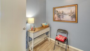 Ein Zimmer mit Schreibtisch, Stuhl, Lampe und einem Bild an der Wand.