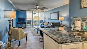 Eine moderne Küche mit Marmorarbeitsplatte, ein Essbereich mit Sofa und Tisch sowie ein Balkon mit Aussicht.