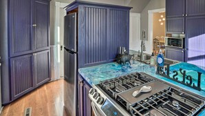 Una cucina con mobili scuri color blu, un piano cottura in acciaio inossidabile e un forno a microonde.