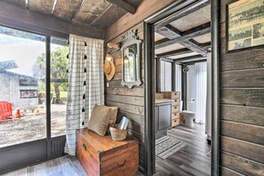 A wooden interior with a wooden bench, a mirror, and a view of the outside. - Authentic Clewiston Home w/ Outdoor Game Area (Clewiston)