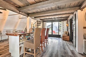 A dining area with a wooden table and wicker chairs, a kitchen area with a white countertop, and a view through a glass door to the outside. - Authentic Clewiston Home w/ Outdoor Game Area (Clewiston)