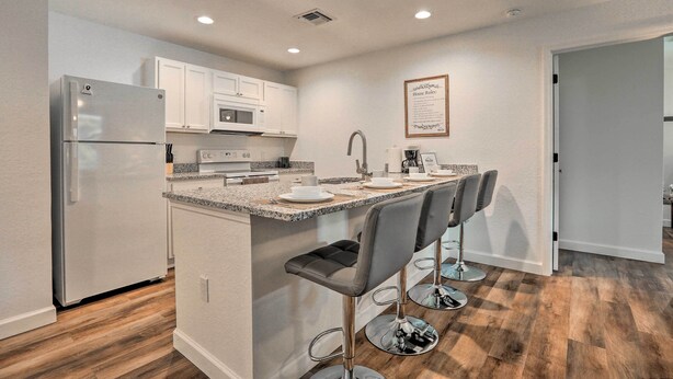 A modern kitchen with white cabinets, stainless steel appliances, and a granite countertop.