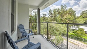A balcony with two chairs and a table, overlooking a green landscape and trees.