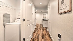 A laundry area with a washing machine and dryer, a hanging rack, and a kitchen area with a sink and countertop.
