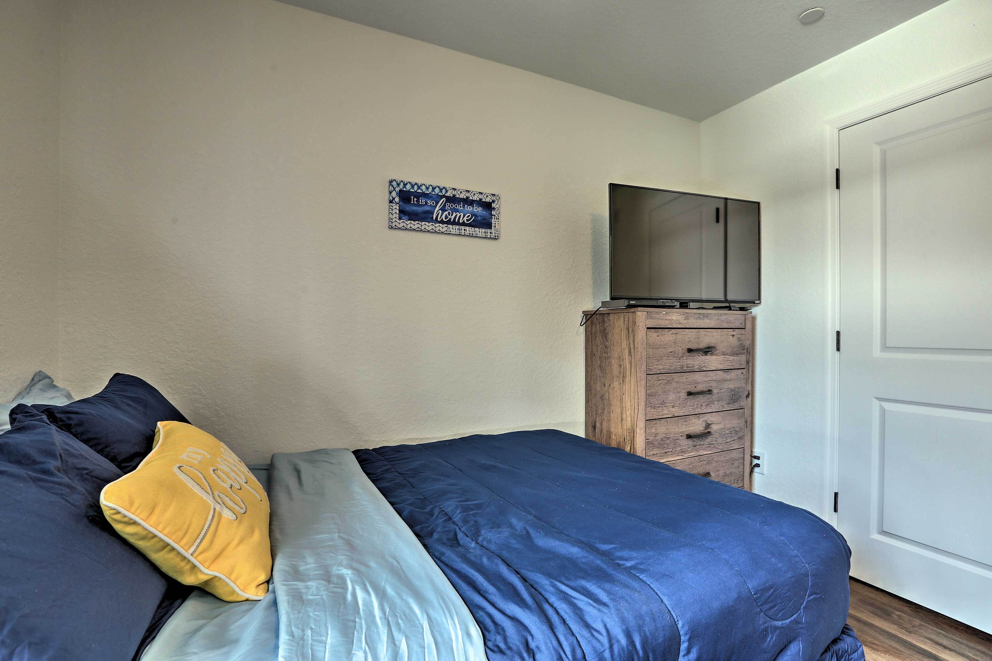 A bedroom with a bed, a TV on a wooden cabinet, and a door.