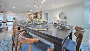 A modern dining area with a long table, wooden chairs, and a chandelier. - Outdoor Oasis! Group Getaway w/ Pool in Brandon (Brandon)