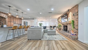 A modern kitchen with wooden cabinets, a brick fireplace, and a dining area with bar stools. - Outdoor Oasis! Group Getaway w/ Pool in Brandon (Brandon)