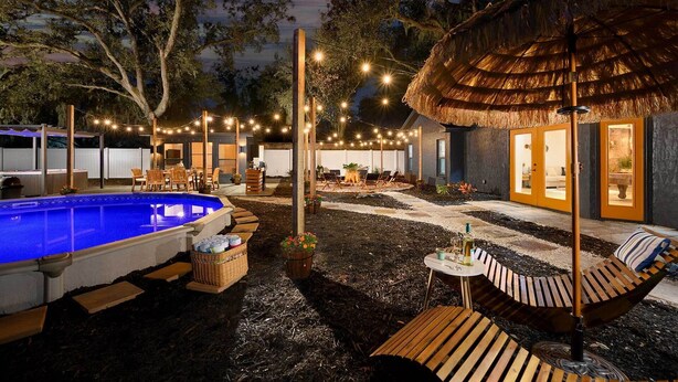 A pool area with lounge chairs and a thatched-roof structure. - Outdoor Oasis! Group Getaway w/ Pool in Brandon (Brandon)