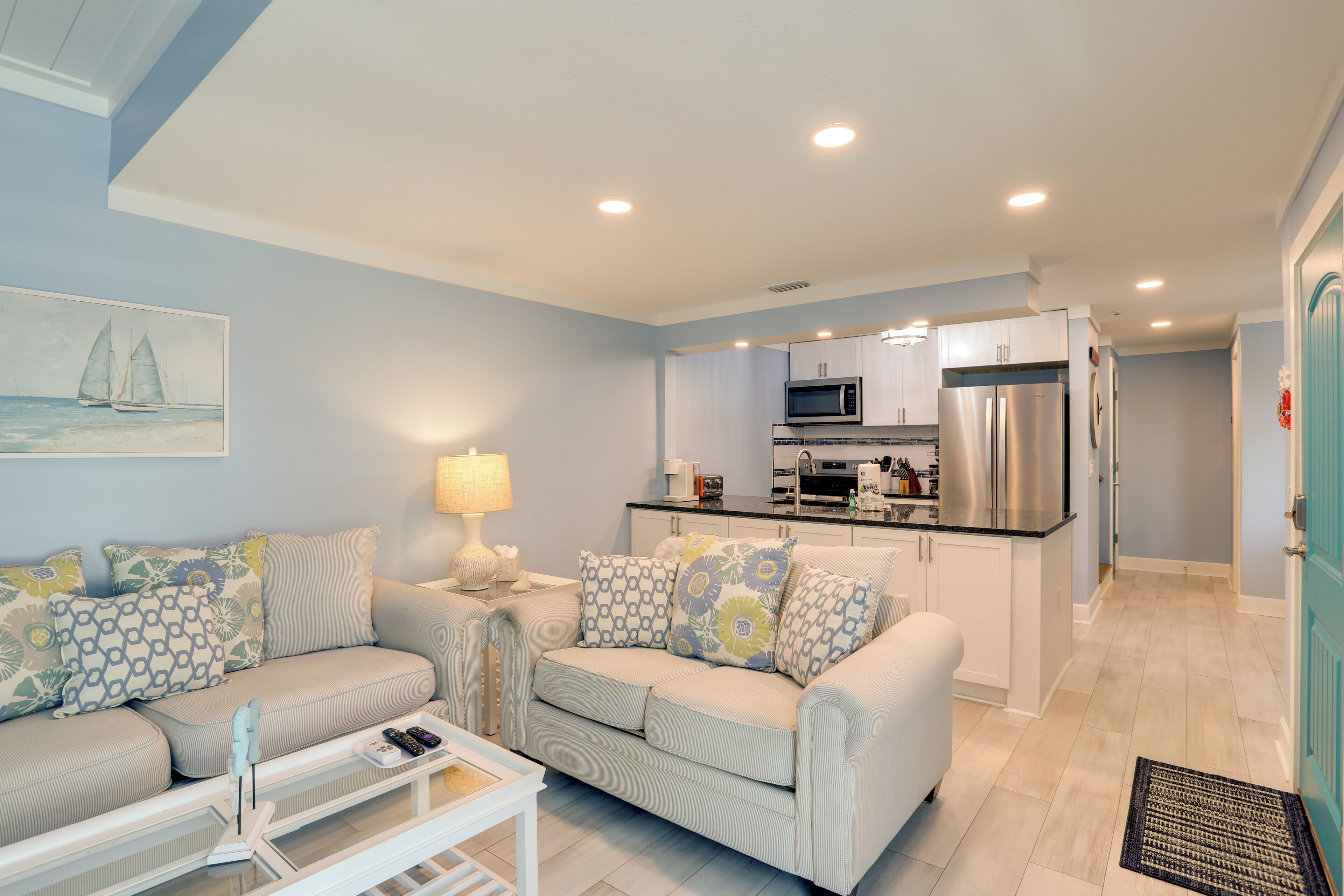 A compact living space with a sofa, coffee table, and a kitchen area with appliances.