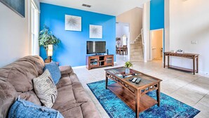 A living room with a brown sofa, a coffee table, and a TV on a wooden stand. - Dog-friendly Kissimmee Home w/ Lanai + Pool! (Kissimmee)