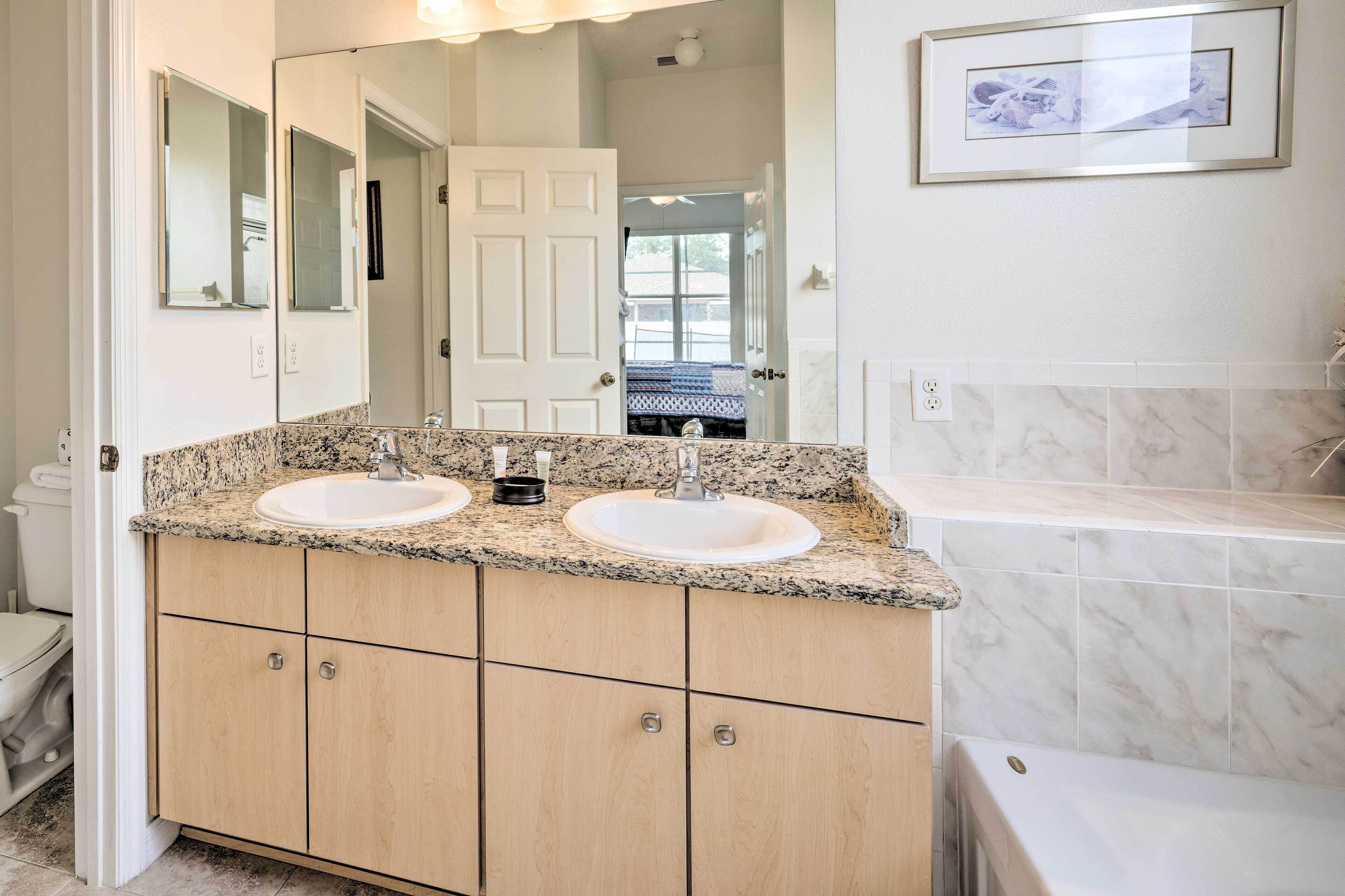 A bathroom with two sinks, a bathtub, and a large mirror.
