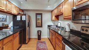 A kitchen with wooden cabinets, stainless steel appliances, and a black countertop. - Cincinnati Home, Patio w/ Downtown Views! (Cincinnati)