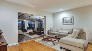 A living room with a sofa, coffee table, and a city view through large windows. - Cincinnati Home, Patio w/ Downtown Views! (Cincinnati)