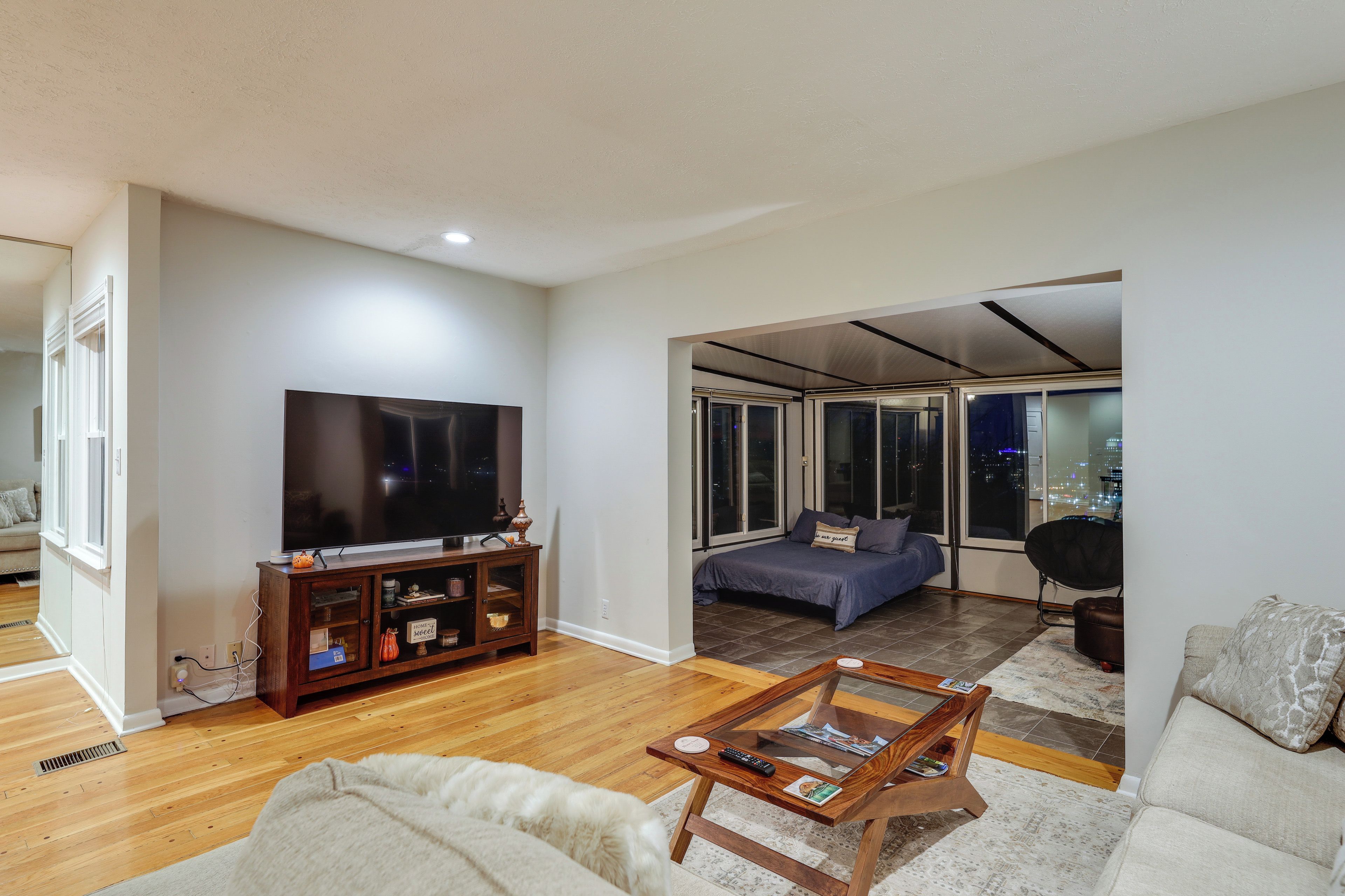 A modern living room with a flat-screen TV, wooden entertainment center, and a cozy sofa.