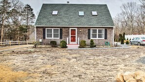 A two-story house with a red door, a small porch, and a front yard. - Martha's Vineyard Escape Near South Beach (Edgartown)