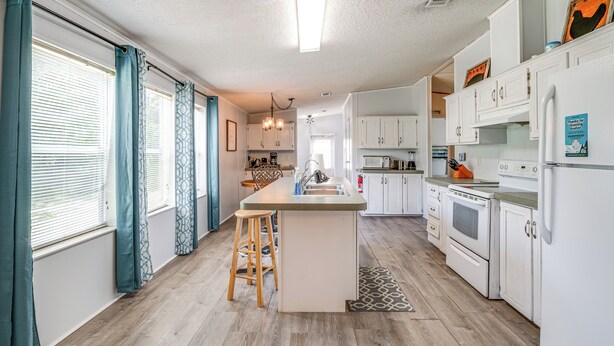 A kitchen with a central island, wooden flooring, white cabinetry, and a built-in oven. - 5 Mi to Homosassa Springs Park: Home w/ Yard! (Homosassa)