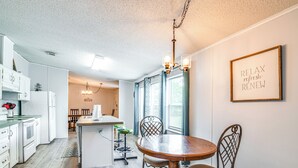 A modern kitchen with white cabinets, a wooden dining table, and a chandelier. - 5 Mi to Homosassa Springs Park: Home w/ Yard! (Homosassa)