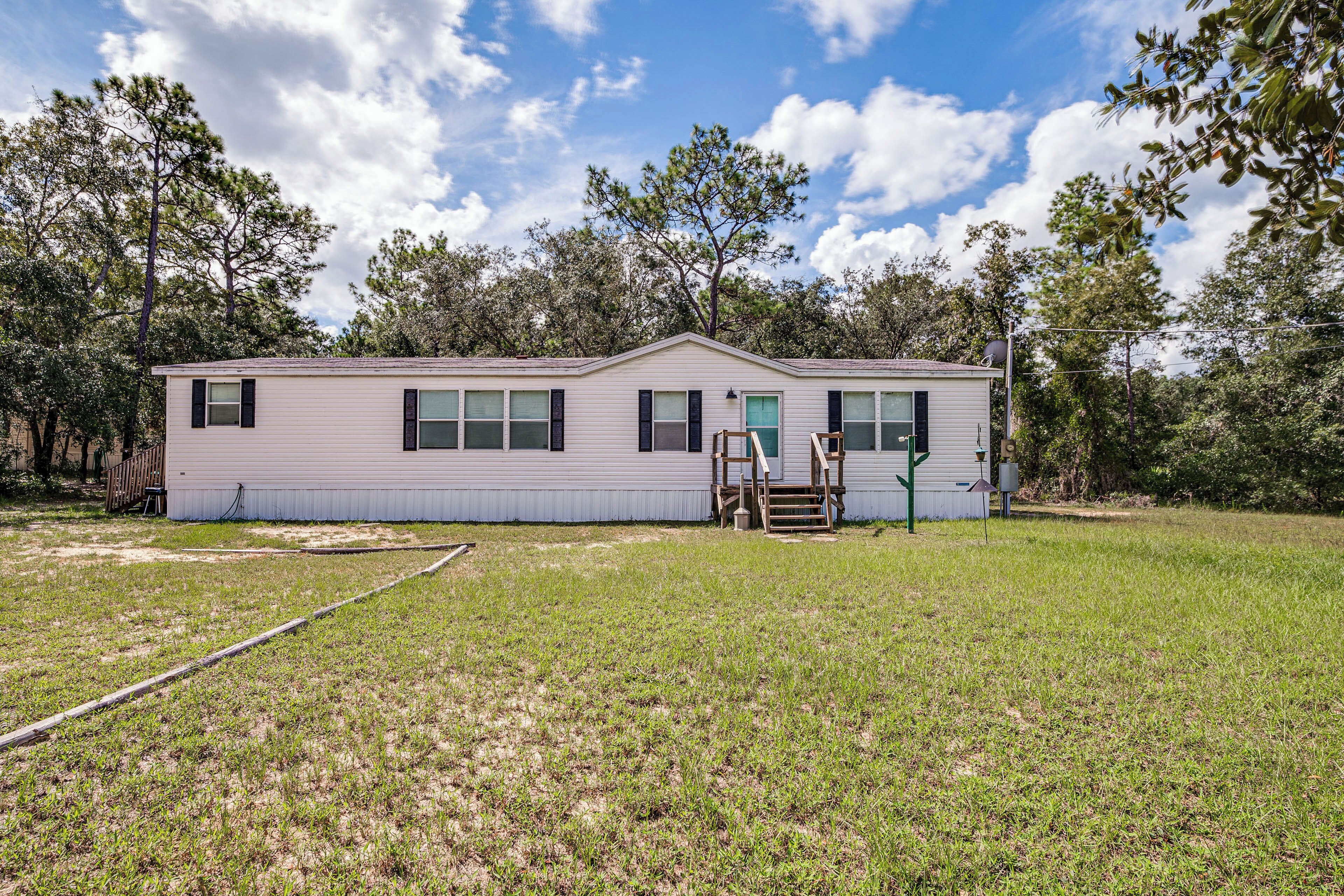 A single-story house with a flat roof, a front porch, and a small yard.