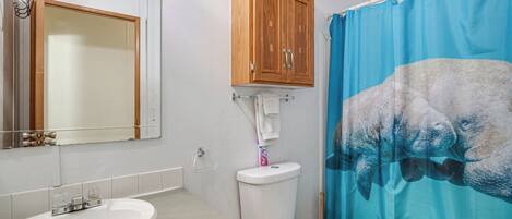 A bathroom with a wooden cabinet, a sink, a toilet, and a blue shower curtain.