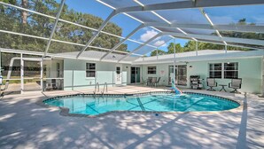 Una piscina interior con zona cubierta, un patio con mobiliario exterior y un edificio con ventanas y puerta.