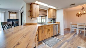 A modern kitchen with wooden cabinets, a central island, and a dining area with a chandelier. - Walk to Lake: Geataway w/ Yard in Inverness (Inverness)