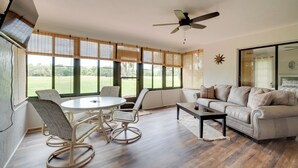 A spacious living room with a round table, two rocking chairs, a beige sofa, and large windows with blinds. - Walk to Lake: Geataway w/ Yard in Inverness (Inverness)