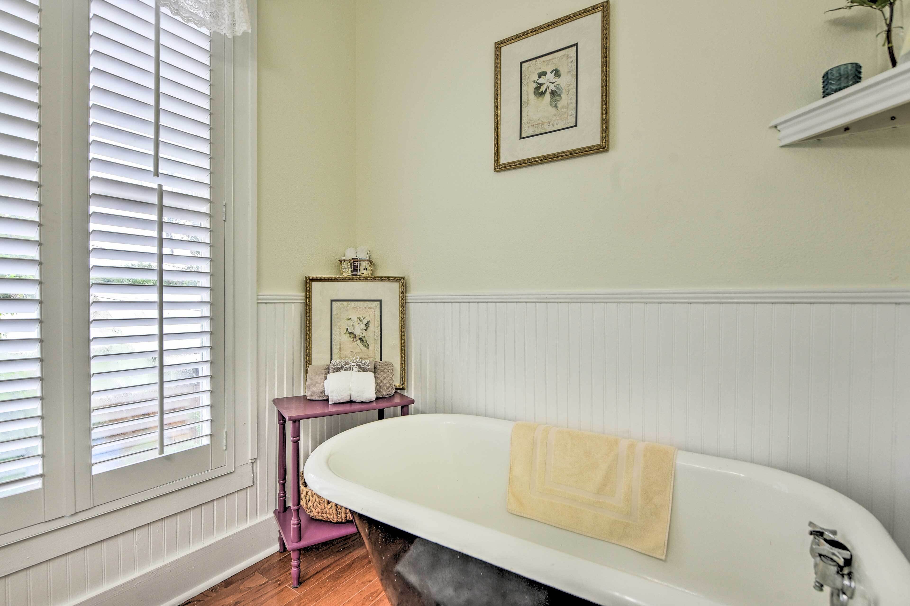 Ein Badezimmer mit einer freistehenden Badewanne, einem Waschtisch mit Spiegel und einem gerahmten Bild an der Wand.