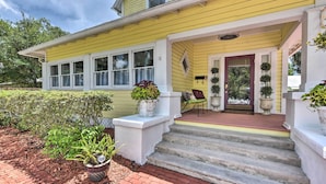 A yellow house with a front porch, steps leading up to the entrance, and potted plants. - Historic Green Cove Springs Home - Walk to Coast! (Green Cove Springs)