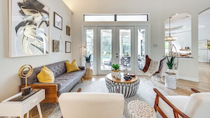 Una sala de estar moderna con un sofá gris, una mesa de centro redonda y un ventanal grande.