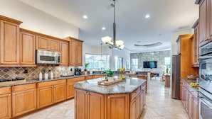 Una cocina amplia con armarios de madera, encimeras de granito y electrodomésticos de acero inoxidable.