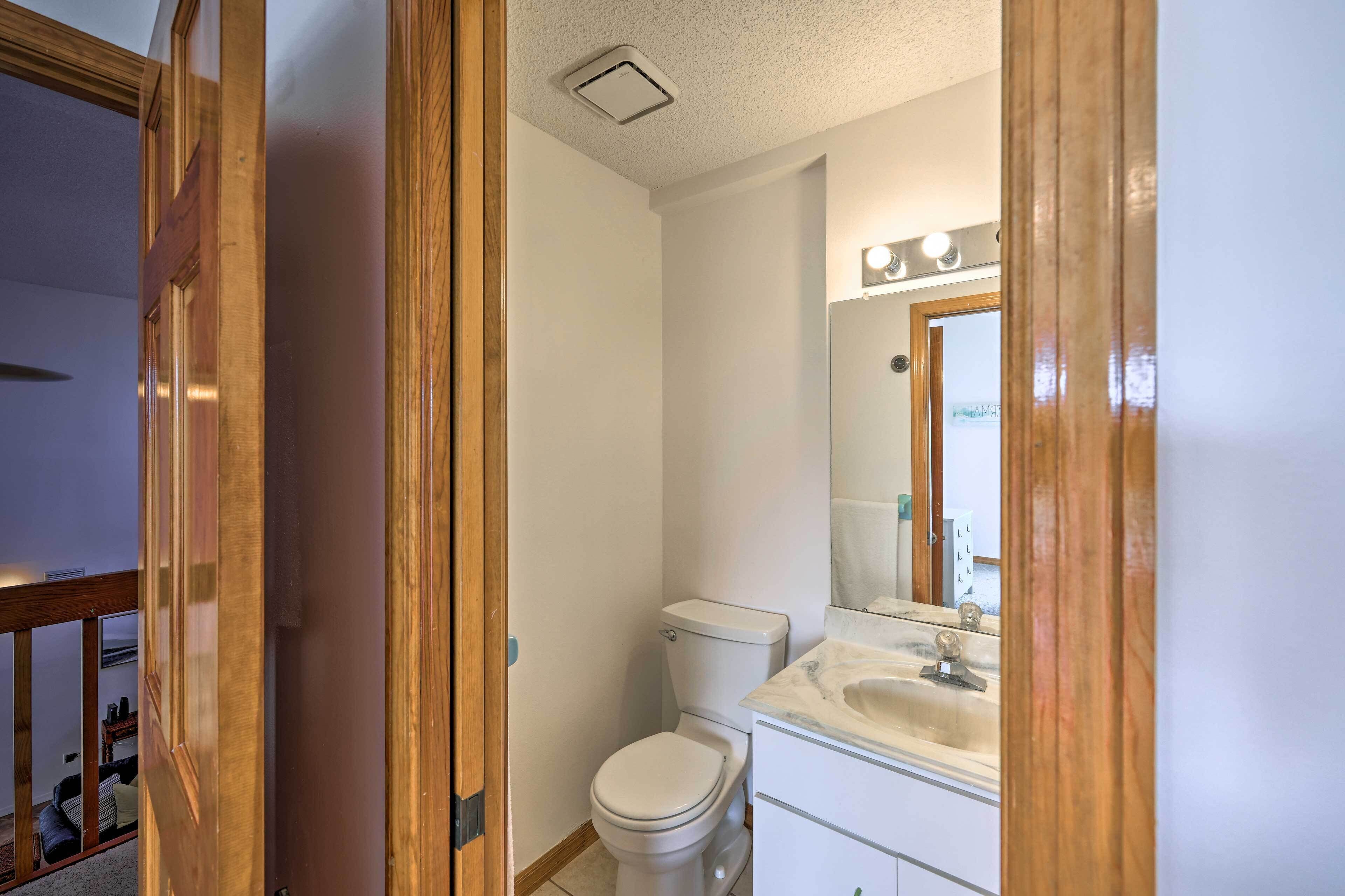 A bathroom with a toilet, sink, and mirror.