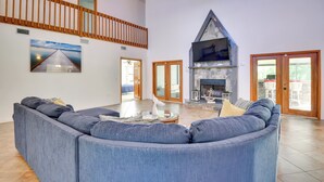 Uma sala de estar ampla com um sofá seccional azul grande, uma lareira e uma escada de madeira.
