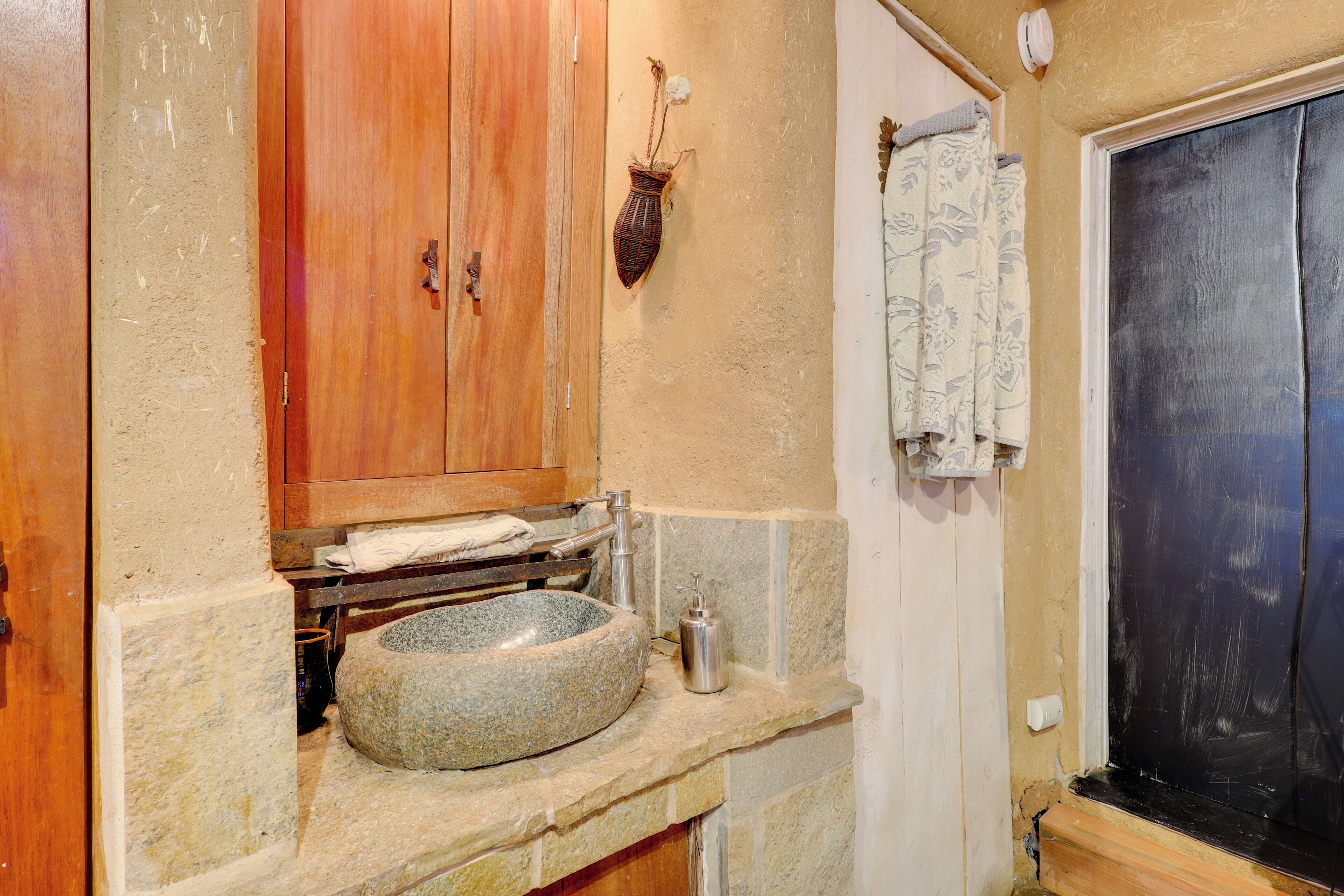 Un baño con lavamanos de piedra, armarios de madera y ventana con marco negro.