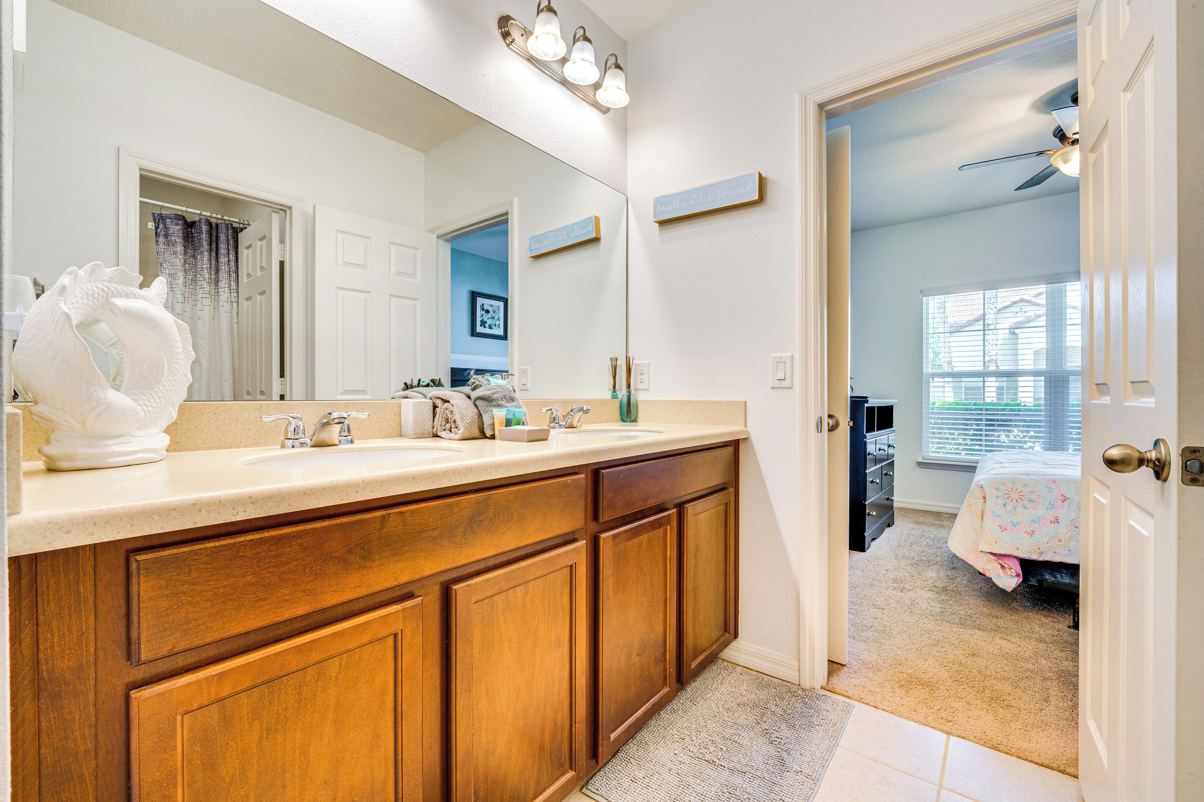 A bathroom with a wooden vanity, a large mirror, and a ceiling fan.