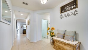 A hallway with a wooden bench, a welcome sign, and a vase with sunflowers. - Central Family Home w/ Lanai < 10 Mi to Disney! (Davenport)