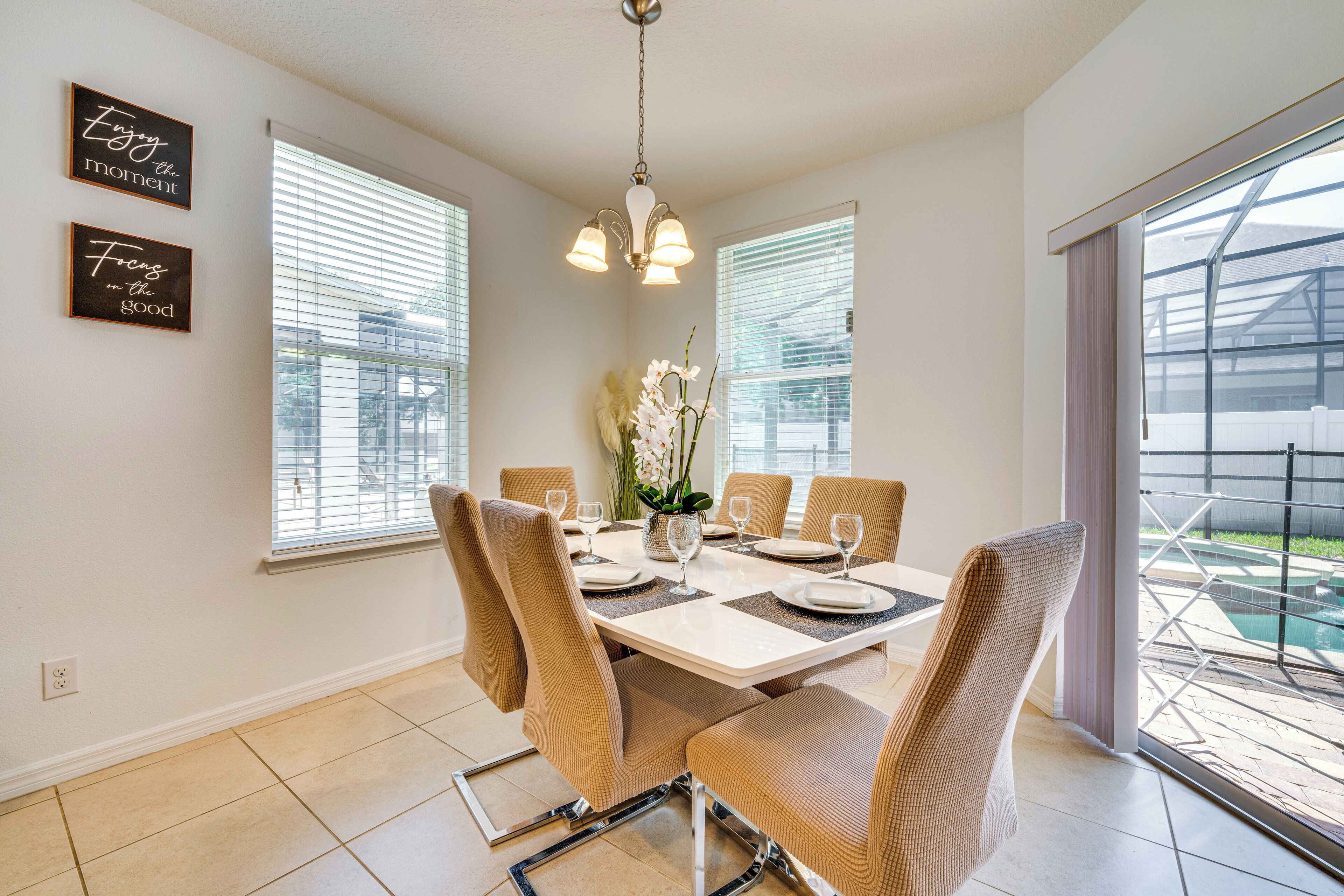 Een eetruimte met een tafel voor zes personen, zes stoelen, een kroonluchter en twee wandborden.