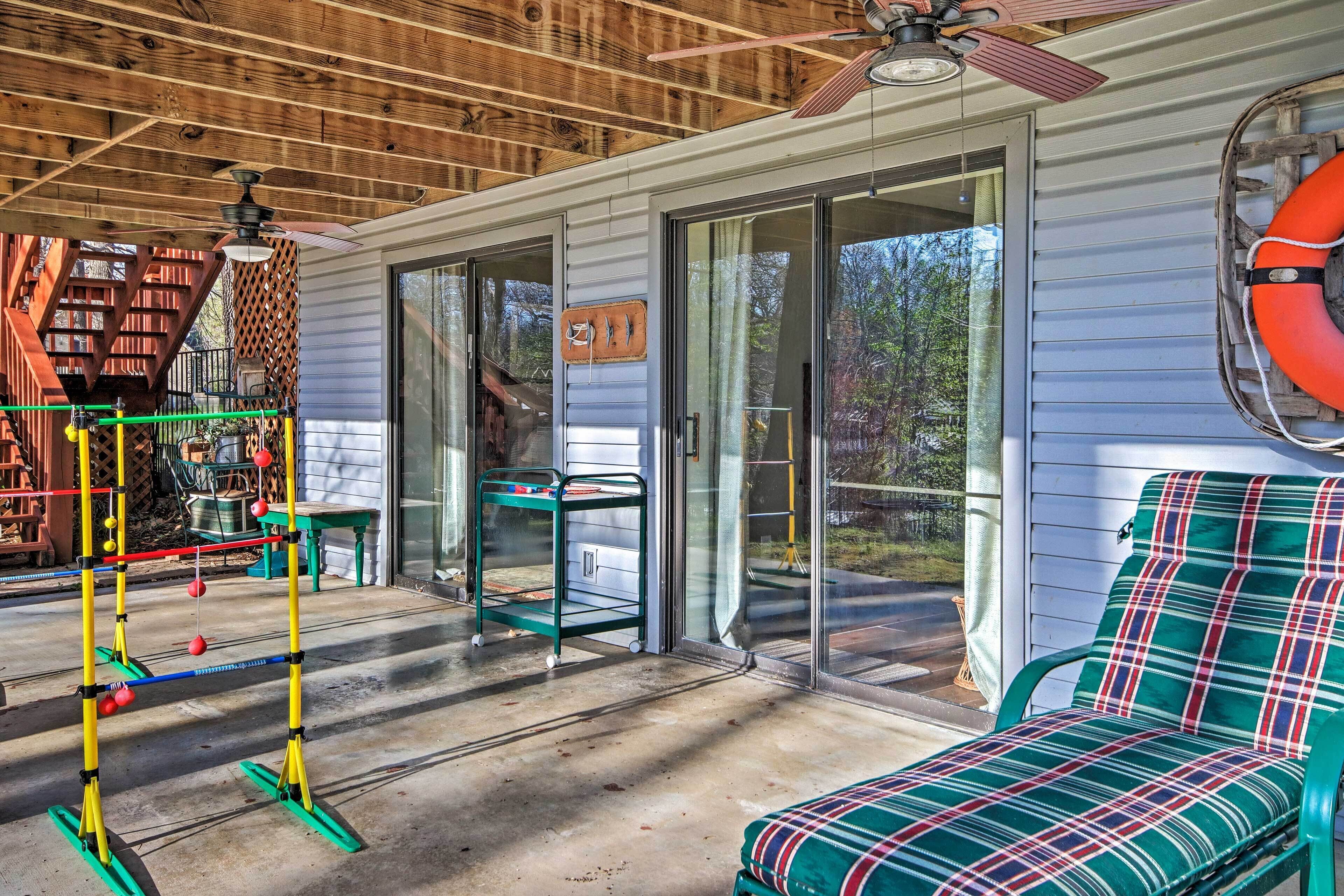 A covered porch with a ceiling fan, a green exercise equipment, a green chair with a plaid cushion, and a lifebuoy on the wall.