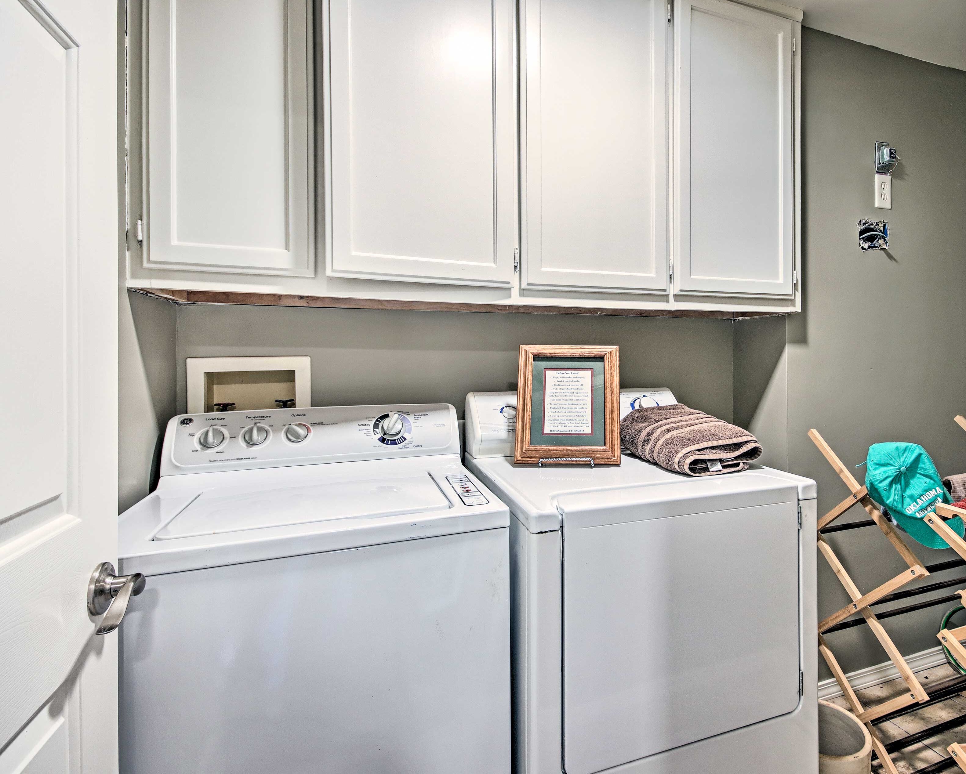 A laundry area with a washer and dryer, a framed sign, and a towel rack.
