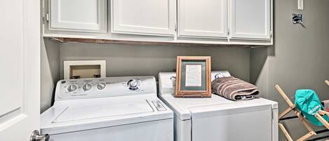 A laundry area with a washer and dryer, a framed sign, and a towel rack.