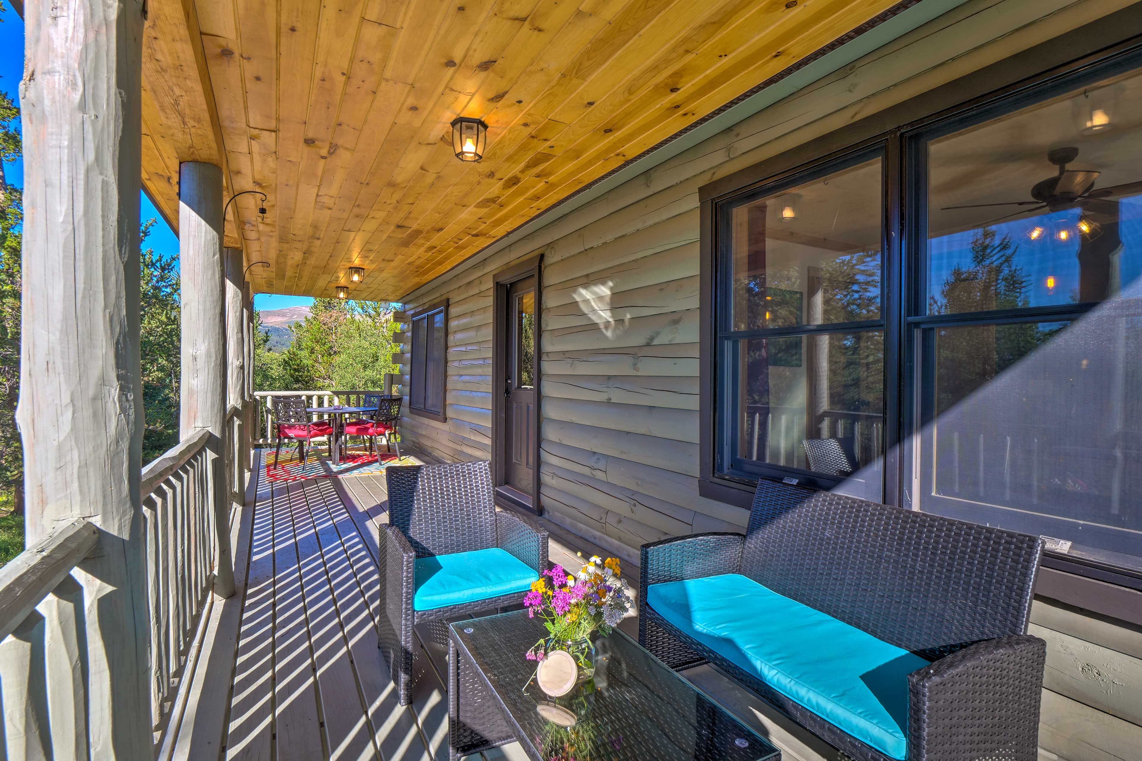 A covered porch with wicker furniture and a table with a vase of flowers.