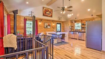 A modern log cabin interior with a dining area, kitchen, and a staircase.