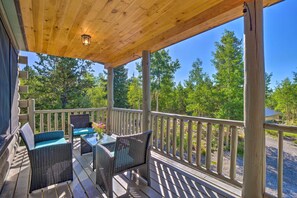 A wooden deck with wicker furniture and a table, overlooking a forested area. - 24-0132 Alma Retreat w/ Deck: 17 Mi to Skiing (Alma)