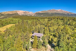 A remote cabin surrounded by dense forest, with a clear view of distant mountains. - 24-0132 Alma Retreat w/ Deck: 17 Mi to Skiing (Alma)