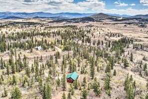 A cabin surrounded by a forest with a mountain range in the background. - Jefferson Cabin w/ Fire Pit: Near Hiking Trails! (Como)