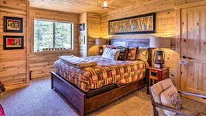 A cozy wooden cabin bedroom with a large bed, a window, and a door. - Jefferson Cabin w/ Fire Pit: Near Hiking Trails! (Como)