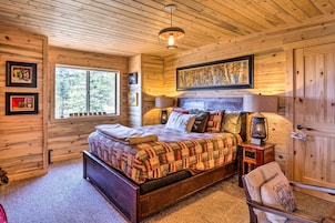 Un dormitorio acogedor de cabaña de madera con una cama grande, una ventana y una puerta.