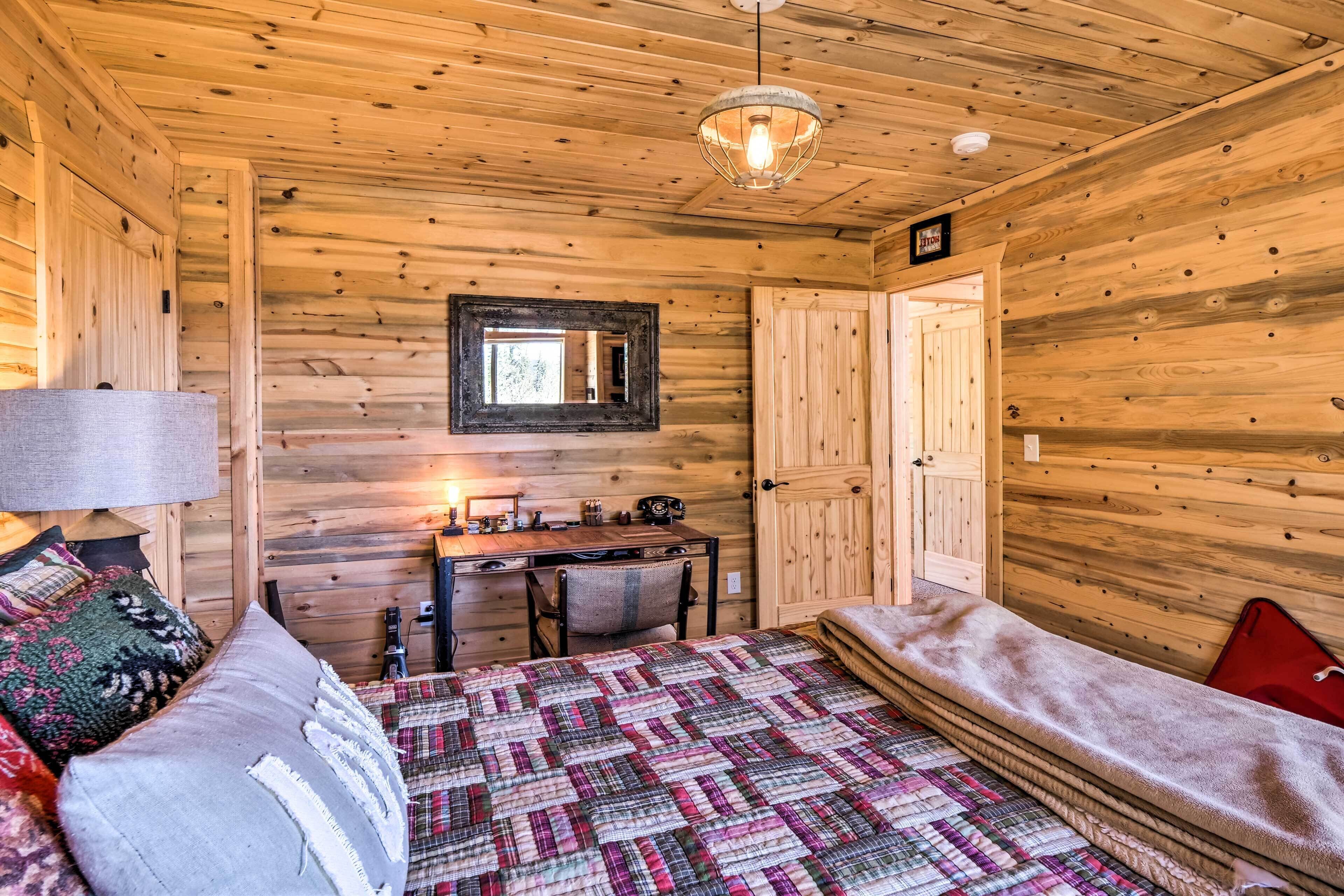 A wooden cabin room with a bed, a desk, and a chair.