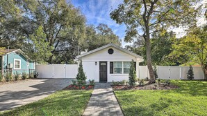 A single-story house with a front yard, a paved walkway, and a small garden with red flowers. - Pet-friendly Mt Dora Home w/ Fire Pit & Patio (Mount Dora)