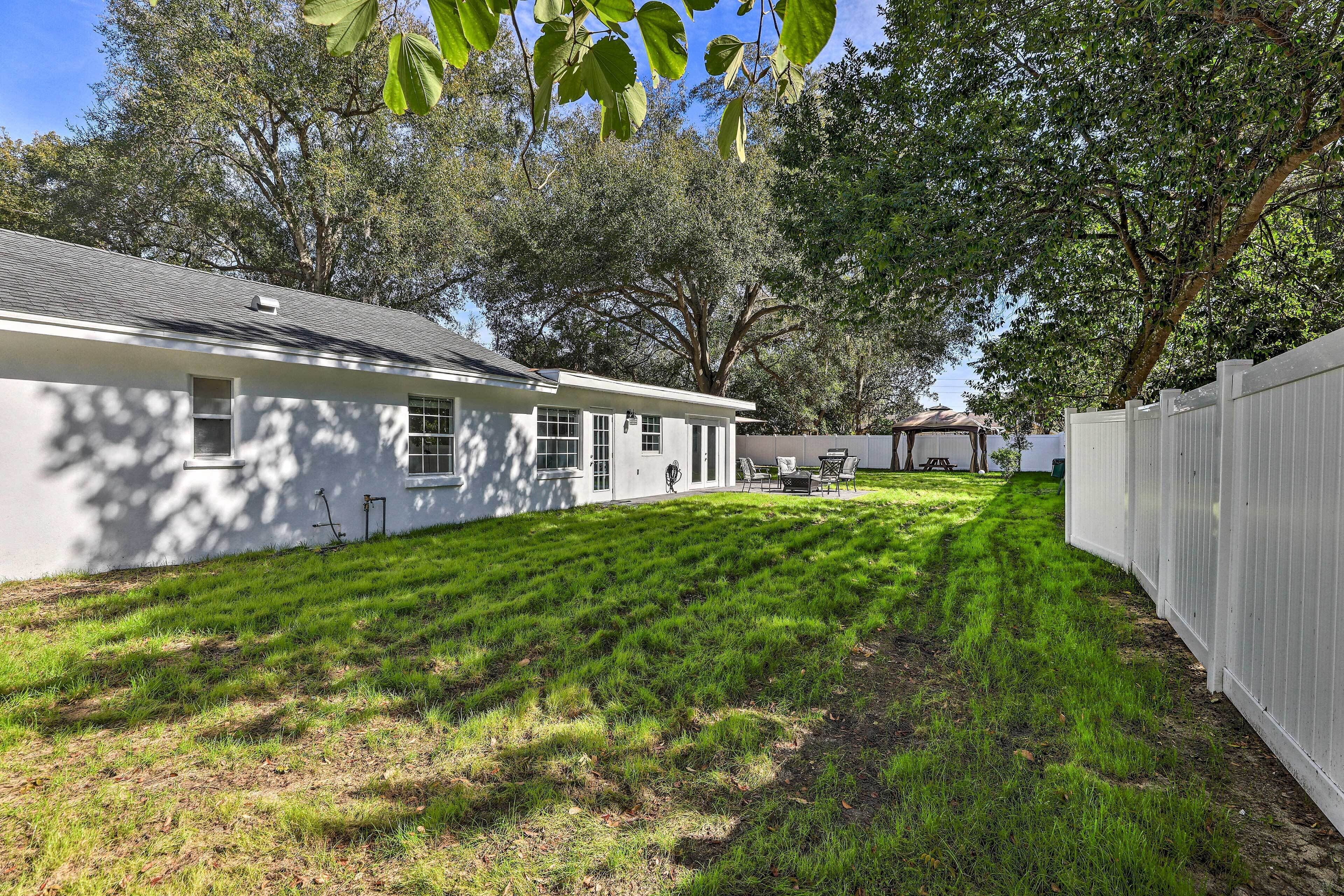 A white house with a well-maintained lawn, a wooden fence, and a patio area with outdoor furniture.